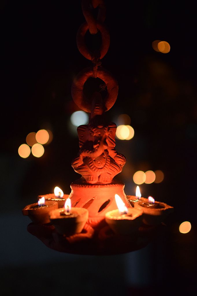 Divali in Trinidad - A lit diya in front of a diety statue