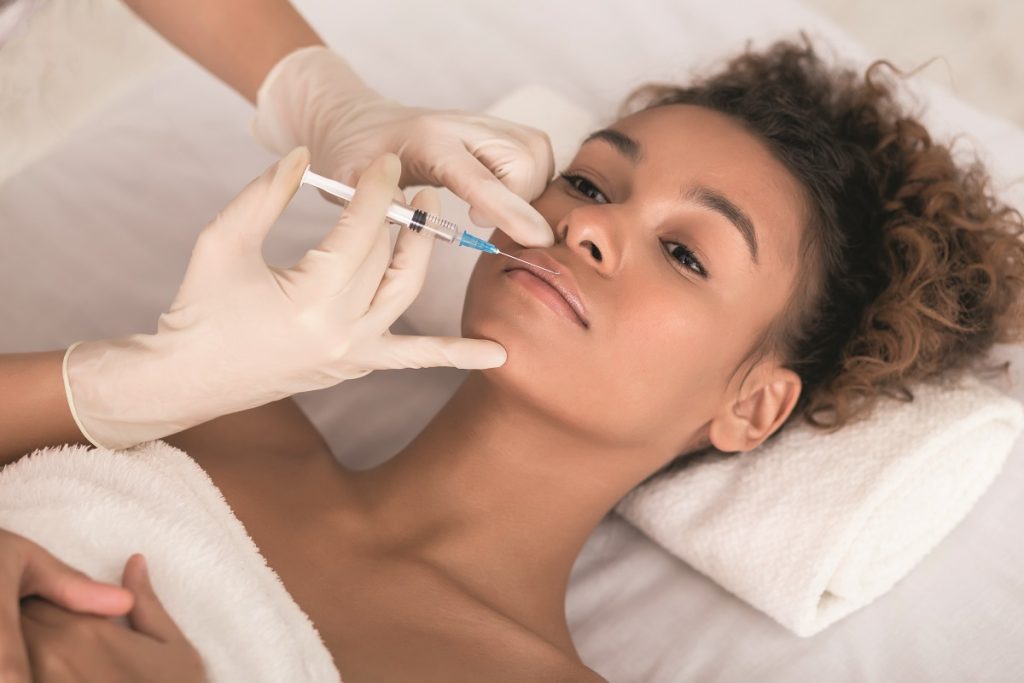 Cosmetic Surgery in the Caribbean -Cosmetologist making beauty injection in lips with syringe.
