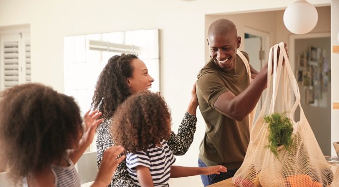 A family coming home with groceries to prepare for clean eating.