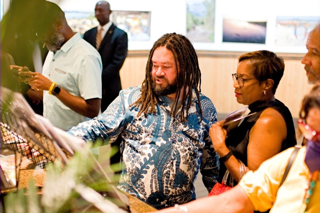 Pieces of Jamaica Photo Exhibit Opens at Island SPACE Caribbean Museum - Artist David I. Muir showing off his book.