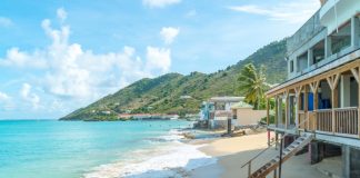 A beach house built on the sand in the Caribbean. The house has a wooden staircase leading down to the shoreline.