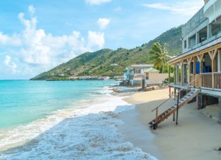 A beach house built on the sand in the Caribbean. The house has a wooden staircase leading down to the shoreline.