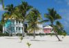A row of colorful beach houses on the beach in the Caribbean with views of tall palm trees and white sands