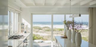 A beach house's beautiful kitchen. The space is painted white and features high-quality appliances and indoor plants.