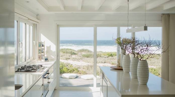 A beach house's beautiful kitchen. The space is painted white and features high-quality appliances and indoor plants.