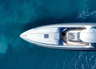 The deep-blue sea with a yacht vacation charter cruising through the waves. The charter is white with a roof and deck.