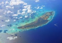 An aerial view of Anegada, a Caribbean island in the British Virgin Islands. White clouds hover above the island.