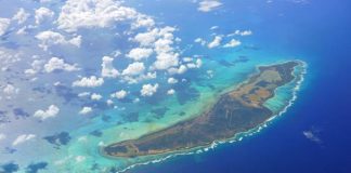 An aerial view of Anegada, a Caribbean island in the British Virgin Islands. White clouds hover above the island.