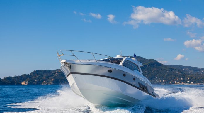 A sport motor boat making a sharp, fast turn on the ocean. There is a tropical, lush island behind the boat.