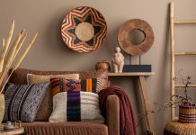 An interior design display of cultural living room decor with colorful pillows, a brown sofa, a wooden bench, and wall decor.