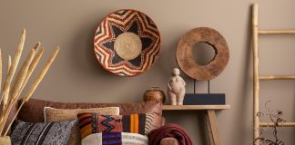 An interior design display of cultural living room decor with colorful pillows, a brown sofa, a wooden bench, and wall decor.