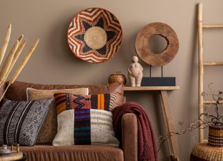 An interior design display of cultural living room decor with colorful pillows, a brown sofa, a wooden bench, and wall decor.