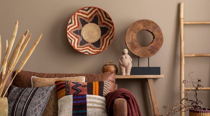 An interior design display of cultural living room decor with colorful pillows, a brown sofa, a wooden bench, and wall decor.