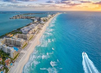 Tips for Breaking Into the Caribbean Travel Market An overhead view of an island in the Caribbean with buildings along the shore and a boat moving through blue water.