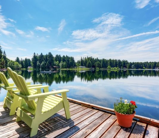 An elegant, sophisticated wedding reception with reflective table tops, white flowers, and string lights over the ceiling.