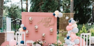 How To Create Instagram-Worthy Event Decor A detailed photo backdrop with pink accents, suitcases, globes, and various balloons. The backdrop says "all you need is love!"