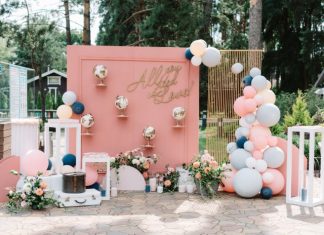 How To Create Instagram-Worthy Event Decor A detailed photo backdrop with pink accents, suitcases, globes, and various balloons. The backdrop says "all you need is love!"